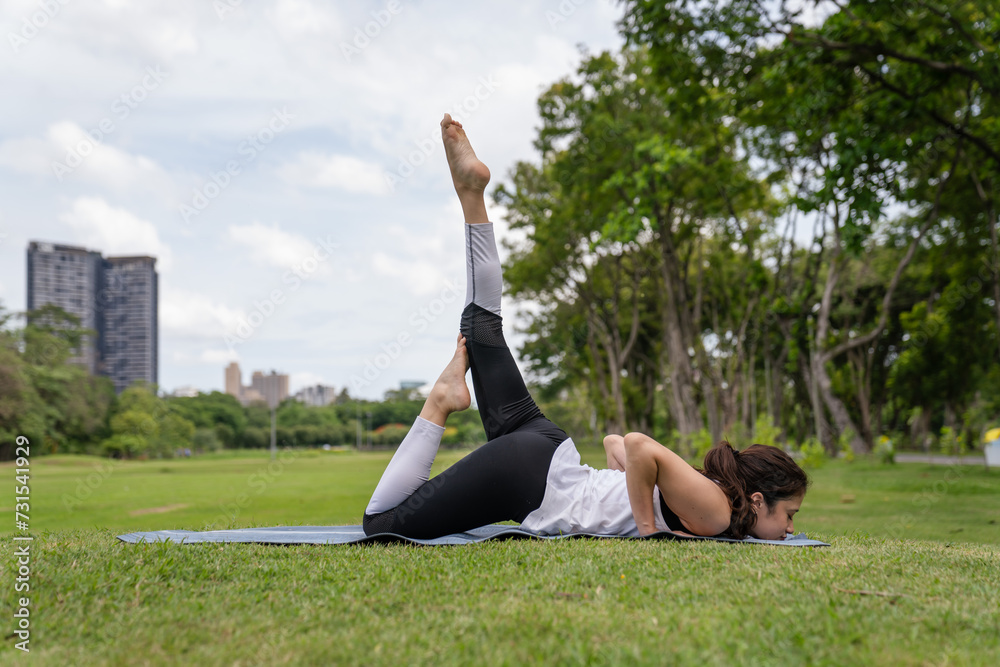Fototapeta premium Young women have beautiful bodies, Playing yoga in an elegant posture, in the green park, is a concept of people's recreation and health care concept. blurred background