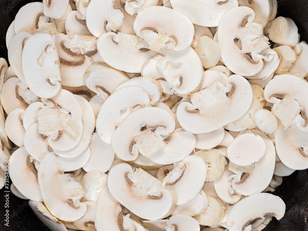 Raw sliced button mushrooms on old frying pan, top view Raw sliced button mushrooms on old frying pan, top view