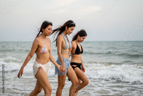 Asian three women friends walking on the beach during summer together.