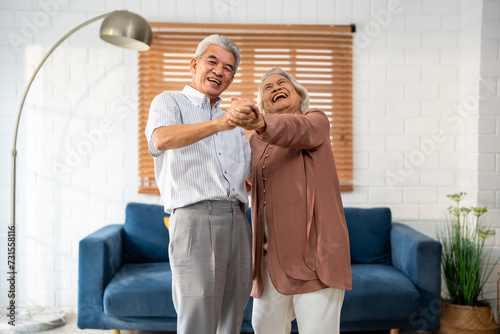 Asian active senior couple enjoy dance together in living room at home. 