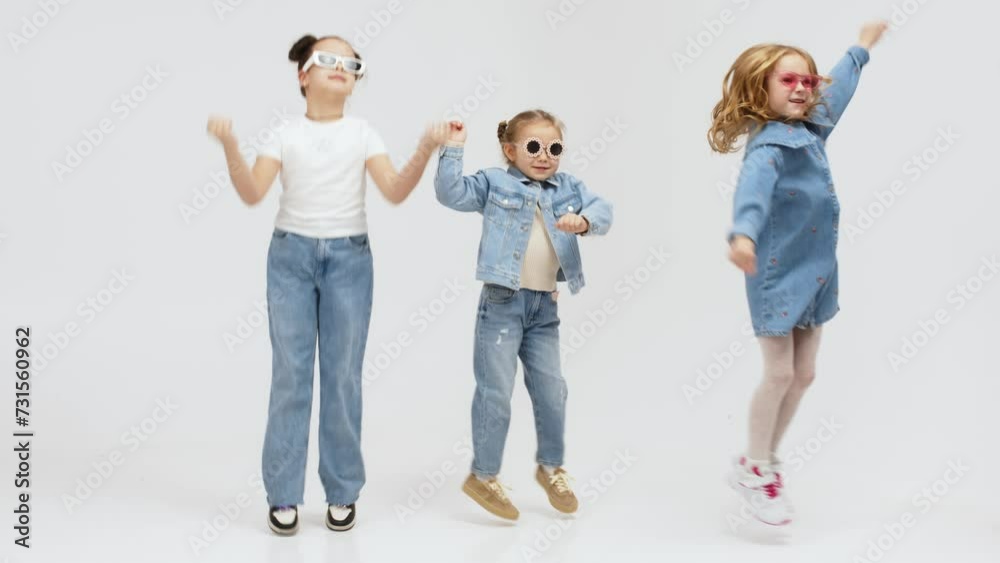 A group of modern, happy children are dancing and having fun on a light isolated background. Concept for clothing advertising, children's shopping and style. A group of modern, happy children are dancing and having fun on a light isolated background. Concept for clothing advertising, children's shopping and style.