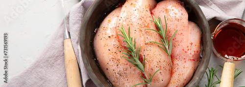 Fotografía Raw marinated chicken meat with rosemary and sauce in a grey bowl