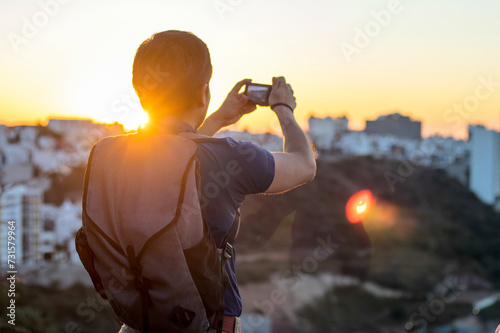 Young man taking a photo with his camera at sunset, with space for text