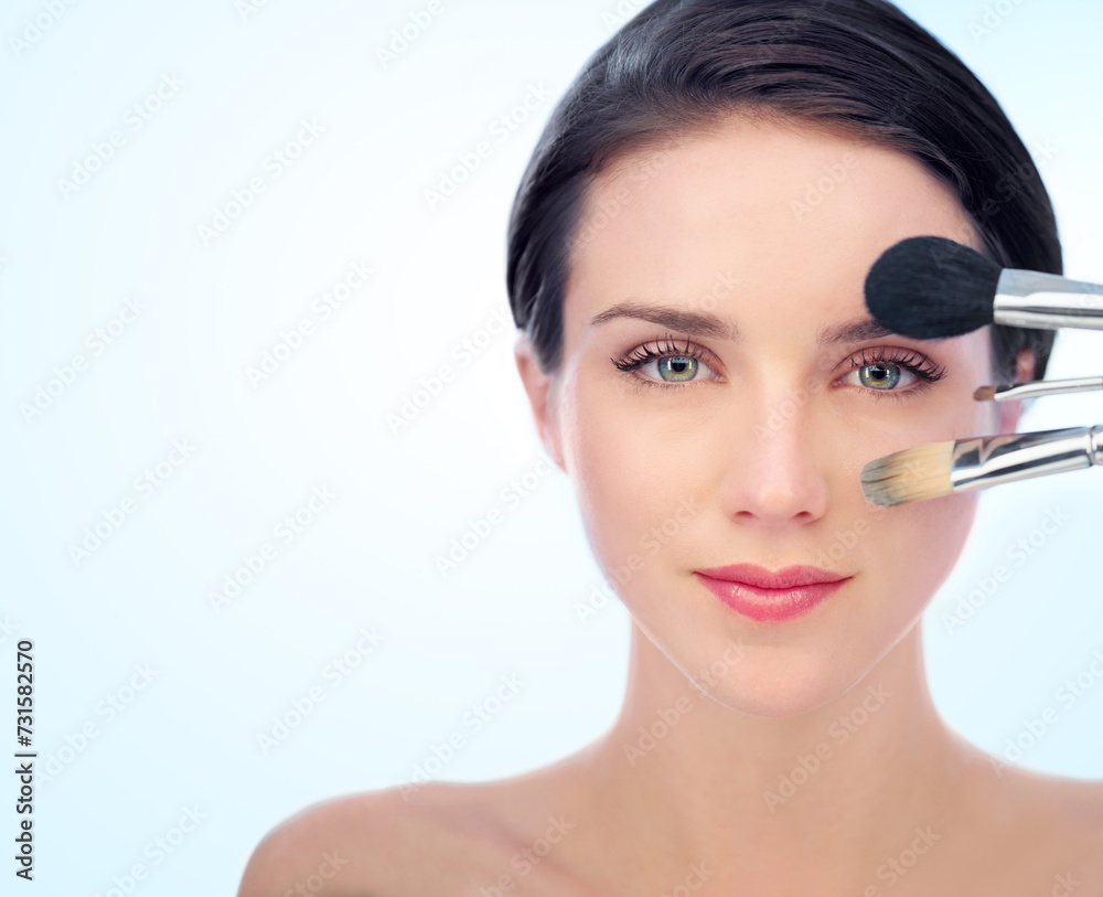 Portrait, beauty and makeup brushes with natural woman in studio on blue background for cosmetology. Face, skincare or cosmetics and confident young model with product for foundation application