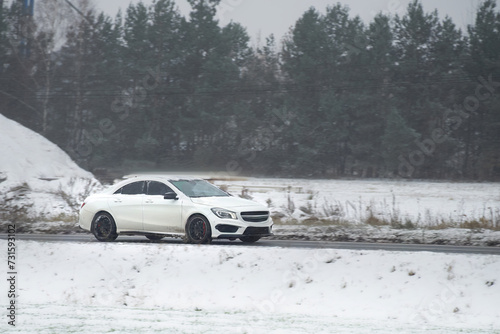 A modern car driving on a snowy highway in winter and tires are essential for safety and performance. drive safely and efficiently in cold weather conditions. a view of a car on a snow-covered road