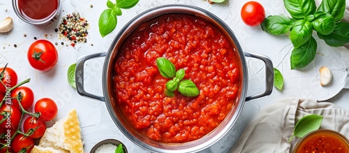 Italian marinara sauce for pasta in a pot, on a white table (top view).