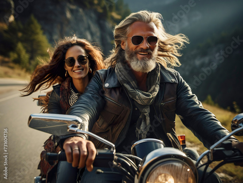 stylish hipster middle age couple - bearded brutal male in sunglasses and leather jacket sitting on a retro motorcycle and sensual girl sitting near, riding on forest road background