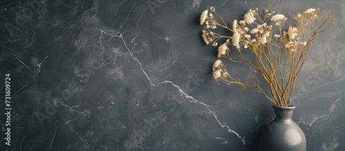 Chamomile flowers dried in a decorative vase become an accent piece on a uniform background of dark marble.