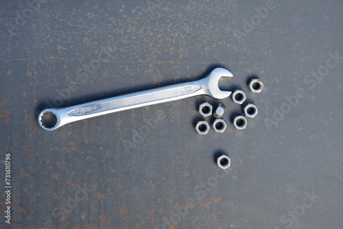 Wrench and nuts on an iron sheet.