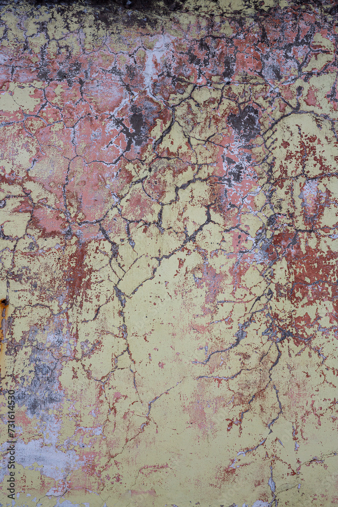 Naklejka premium Peeling paint on the wall. Old concrete wall with cracked flaking paint. Weathered rough painted surface with patterns of cracks and peeling. Grunge texture for background and design. High resolution.