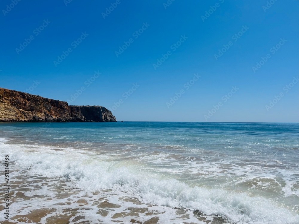 Rocky coast of the ocean bay, clear blue sky, ocean horizon, rocks