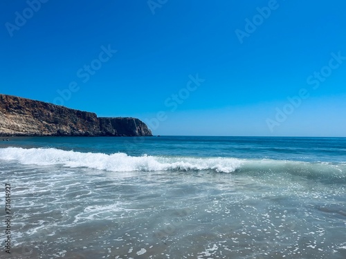 Rocky coast of the ocean bay, clear blue sky, ocean horizon, rocks