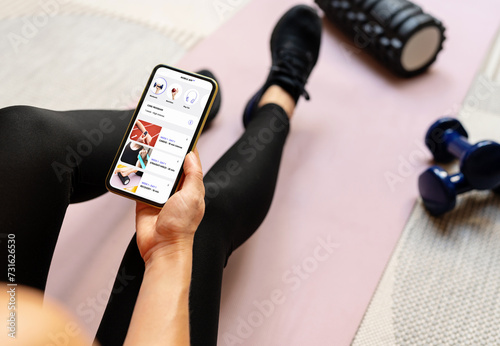 Quadro su tela Woman uses a mobile fitness application on her smartphone