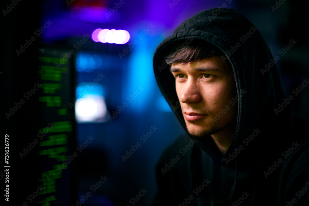 Low Key Lighting Shot Of Male Computer Hacker Sitting In Front Of Screens Breaching Cyber Security Low Key Lighting Shot Of Male Computer Hacker Sitting In Front Of Screens Breaching Cyber Security
