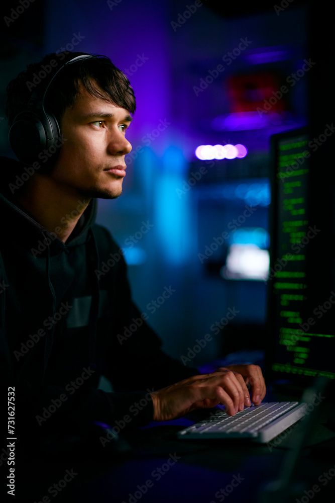 Low Key Lighting Shot Of Male Computer Hacker Sitting In Front Of Screens Breaching Cyber Security Low Key Lighting Shot Of Male Computer Hacker Sitting In Front Of Screens Breaching Cyber Security