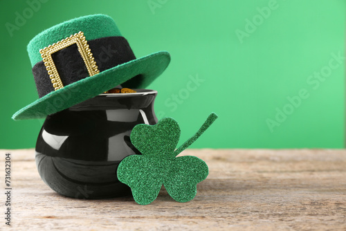 St. Patrick's day. Pot of gold with leprechaun hat and decorative clover leaf on wooden table. Space for text