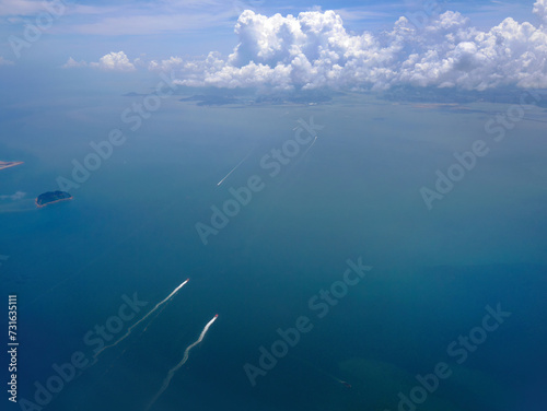 Aerial shot of sea water in turquoise color with cloudscape in the sky, many ships or cruise onboard below, tranquil sky scene, earth from above photo