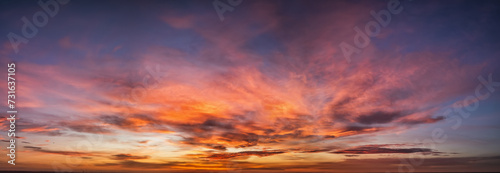 A vibrant sunset or sunrise sky panorama with cloudscape in soft magenta, pink and orange tones as a background or texture © moofushi