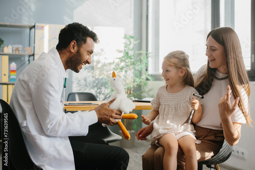 Happy little girl, mother and family doctor playing fun game with toy and neurologist's hammer.