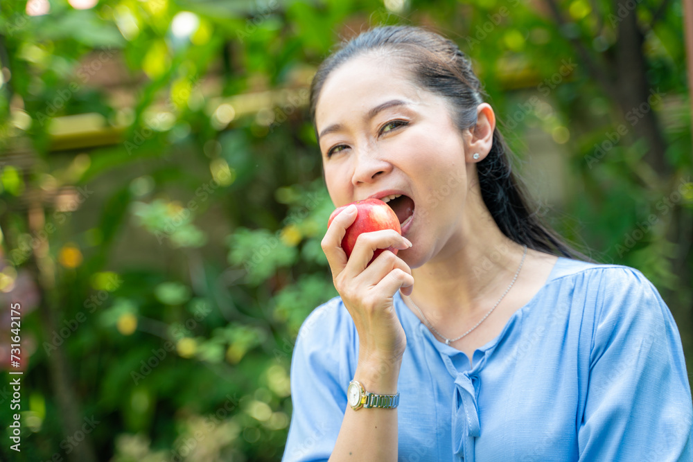 Beautiful cheerful asian woman eating fresh apple in green park Beautiful cheerful asian woman eating fresh apple in green park
