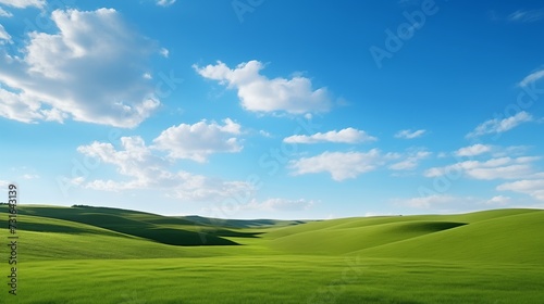 An idyllic and tranquil nature landscape capturing rolling green hills beneath a clear blue sky adorned with wispy clouds. 