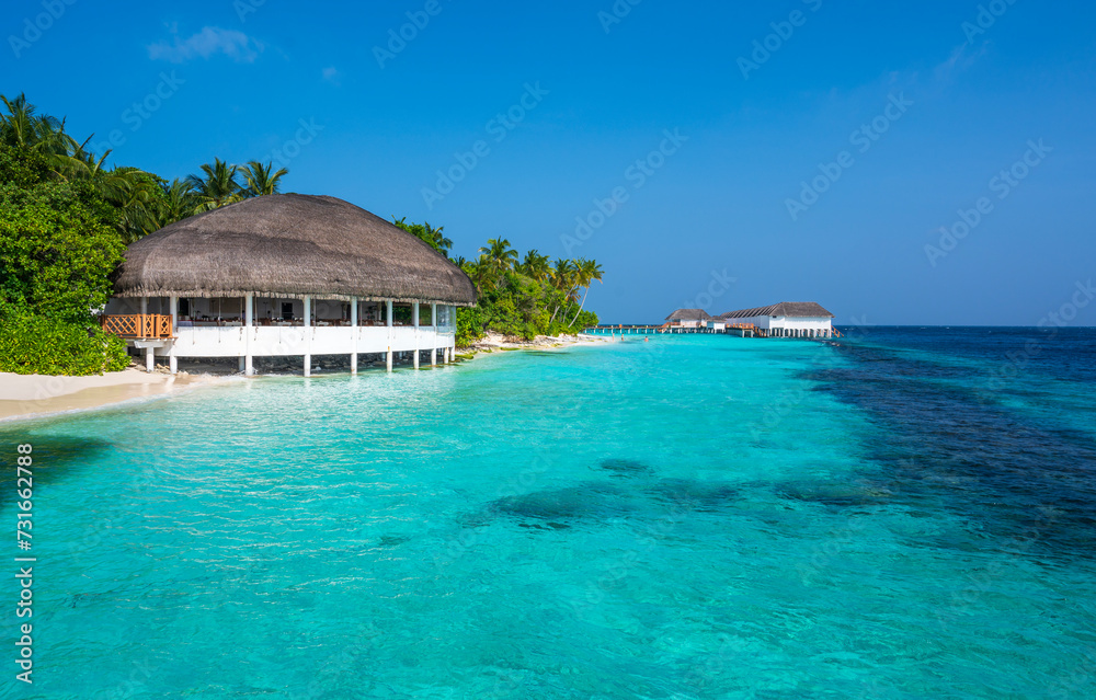 Tropical structure with a thatched roof on a beautiful sandy beach. In the background are apartments above sea level.