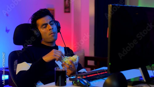 A professional Indian gamer relaxing after a long virtual playing session - leisure activity  relax  chill  refreshing. Young mature adult binge watching web series with snacks and drinks - popcorn...