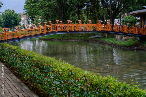 Fototapeta Naklejka Na Ścianę i Meble -  beautiful orange bridge with flowing river in city park.