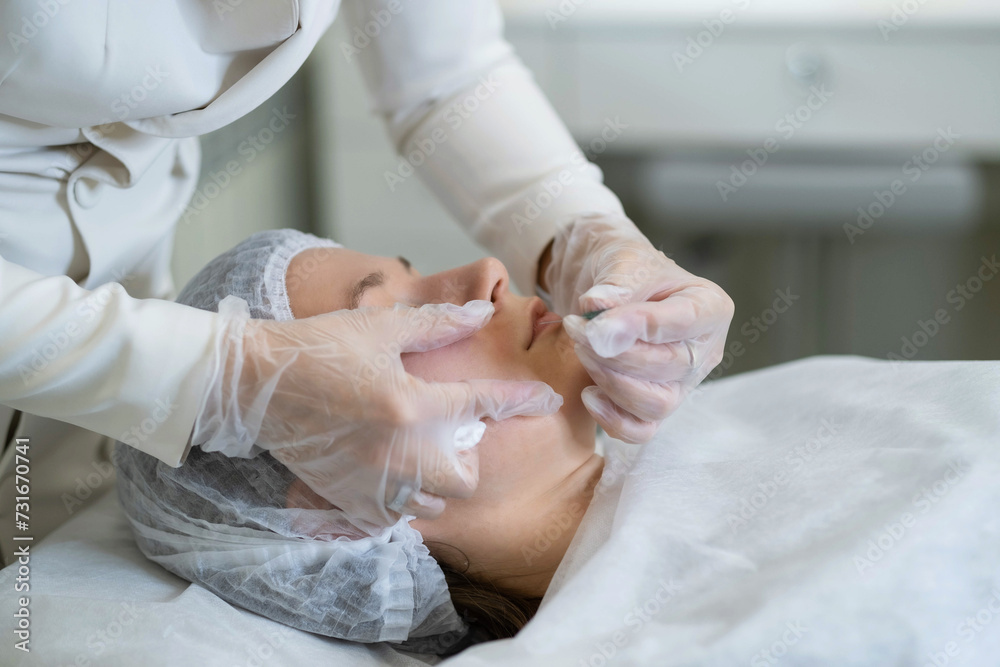 Focused cosmetologist injects treatment for nasolabial creases. This portrays the detail-oriented nature of aesthetic procedures. Focused cosmetologist injects treatment for nasolabial creases. This portrays the detail-oriented nature of aesthetic procedures.