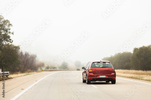 Red car overtaking in the right hand lane in foggy conditions photo