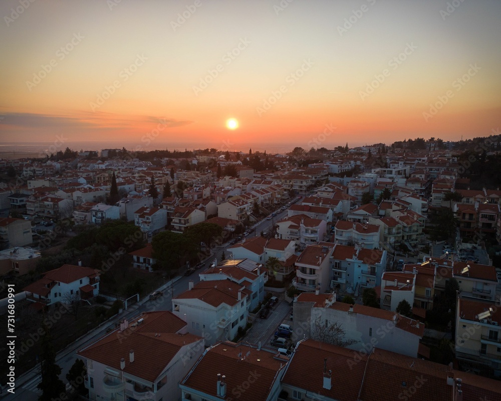 Aerial shot of a town with dense buildings with red roofs at golden sunset