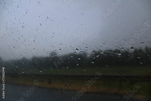 a wet windshield on the side of a road with rain droplets in the air