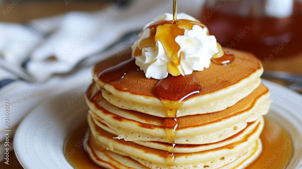 A stack of fluffy pancakes drizzled with maple syrup and topped with a dollop of whipped cream, perfect for a cozy breakfast A stack of fluffy pancakes drizzled with maple syrup and topped with a dollop of whipped cream, perfect for a cozy breakfast