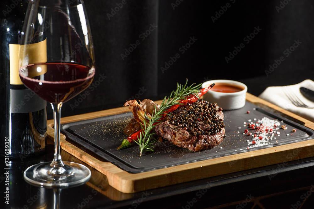 Succulent grilled beef steak with red wine, seasonings, fresh rosemary and grilled vegetables on cutting board Succulent grilled beef steak with red wine, seasonings, fresh rosemary and grilled vegetables on cutting board