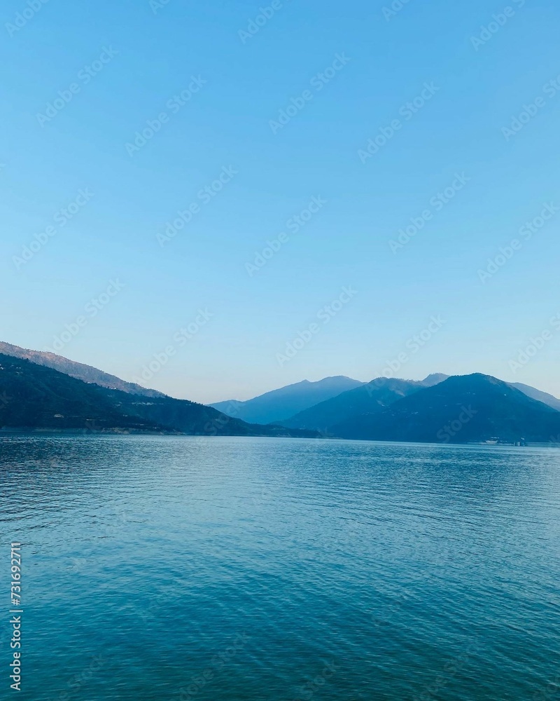 Scenic view of majestic mountains and tranquil blue water against a blue sky