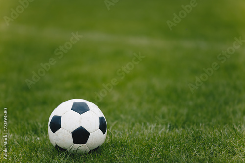 Classic Soccer Ball on Training Pitch. Football Natural Grass Turf. Soccer Stadium in Blurred Background. Young Players Exercising in the Background