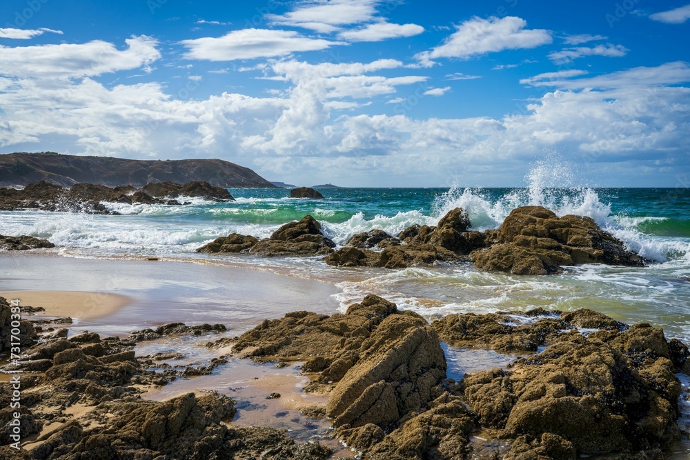 a body of water next to a beach with rocks and sea