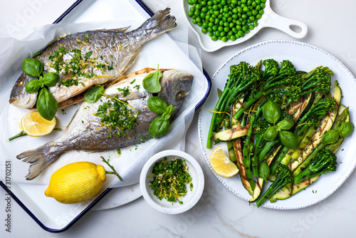 Baked dorado fish with gremolata, italian herb condiment, and grilled green vegetables photo
