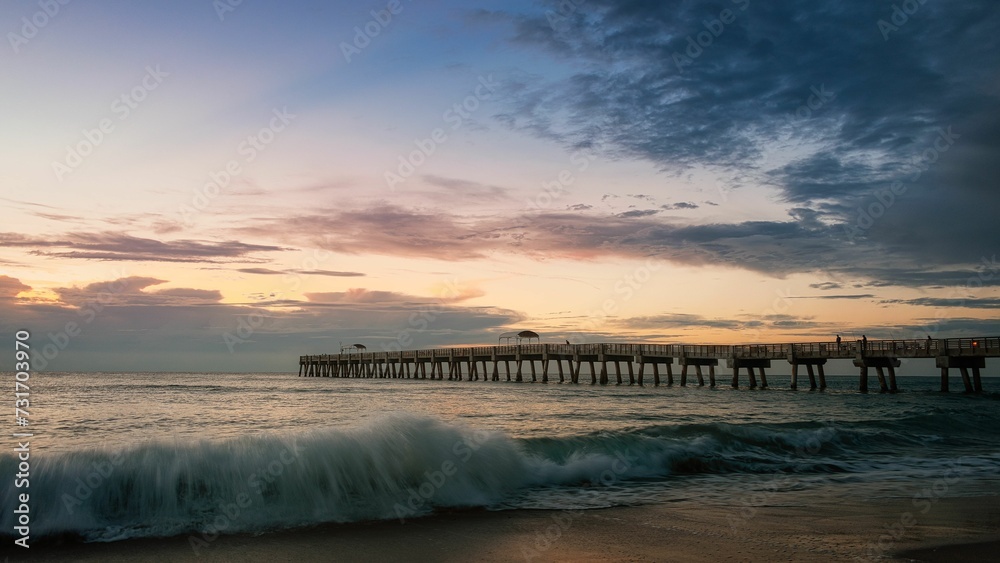 a pier with waves crashing over the shore during the sunset a pier with waves crashing over the shore during the sunset