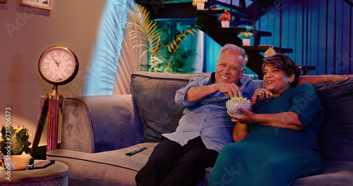 Canvas Print Indian Asian happy gen x old elder couple sitting cozy sofa couch watch movie TV