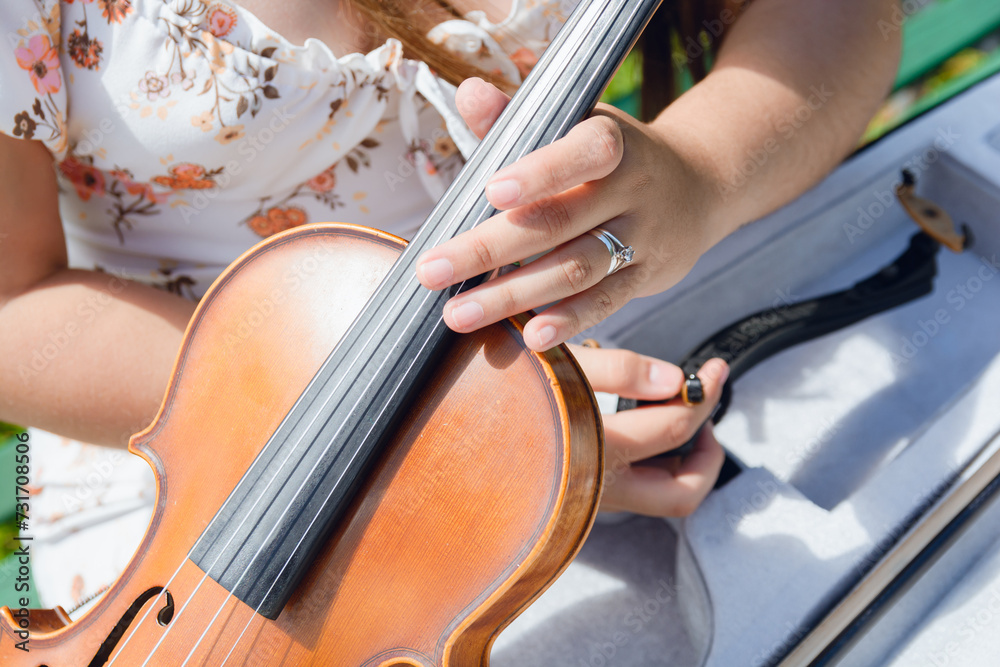 top view closeup of unrecognizable woman holding violin with one hand taking it out of case outdoors top view closeup of unrecognizable woman holding violin with one hand taking it out of case outdoors