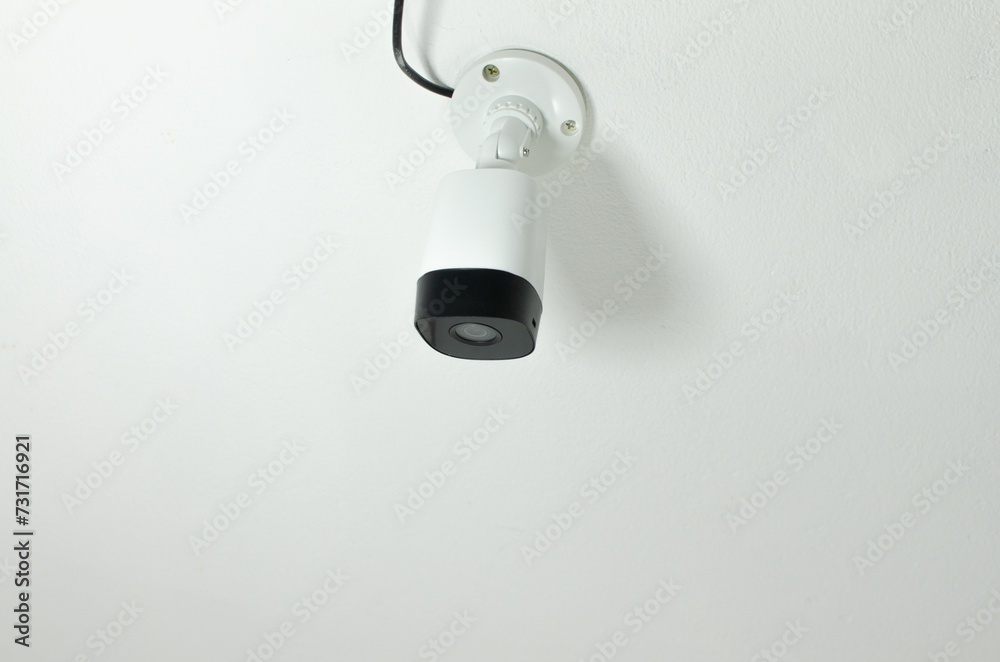 Close-up of a security camera mounted on a wall in a modern office, ready to be used Close-up of a security camera mounted on a wall in a modern office, ready to be used