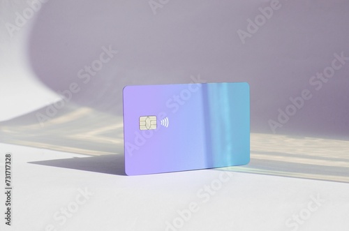 Plastic credit card with chip visible, on top of a table with soft lights and shadows color card. photo