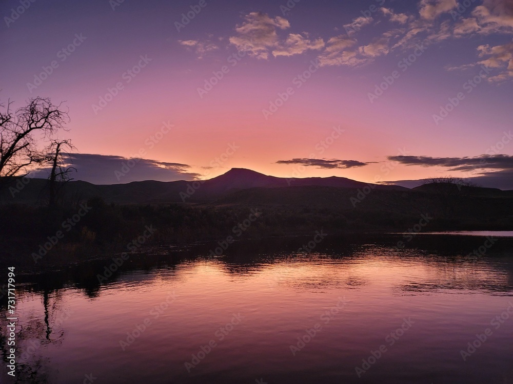 the sun sets on a mountain lake as seen from the shore of a lake