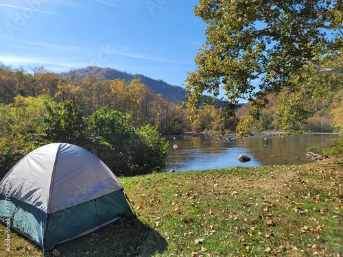 camping tent next to a river with leaves on the ground