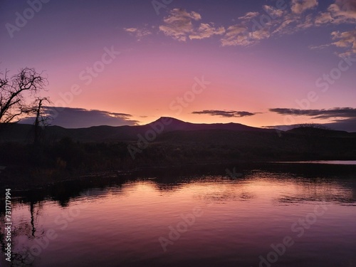 the sun sets on a mountain lake as seen from the shore of a lake