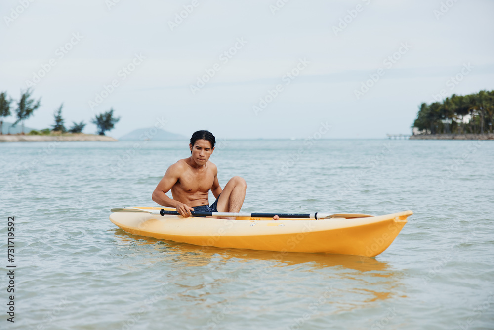 Happy Asian Man Enjoying Kayaking Adventure on a Tropical Beach