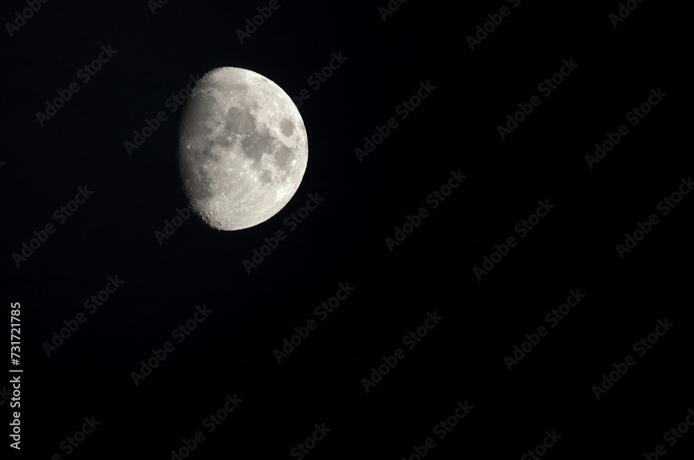 The moon in the waxing gibbous phase against a black sky at night. The moon in the waxing gibbous phase against a black sky at night.