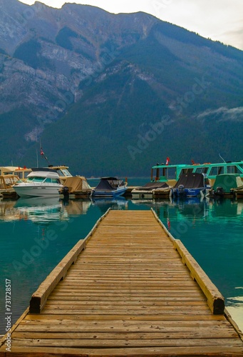 there are many boats docked near the water by the mountains