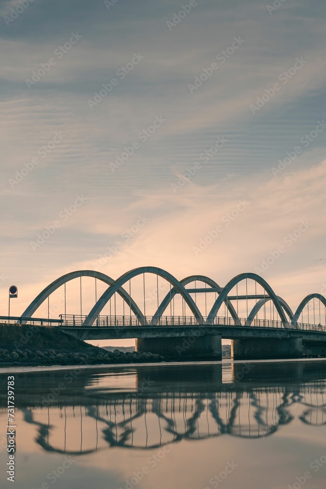 Obraz premium Picturesque arched bridge spanning a tranquil body of water at sunset